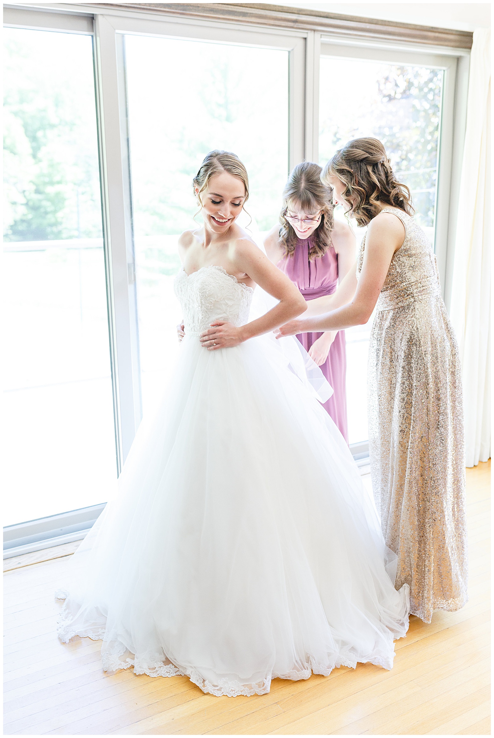 bridesmaids helping bride into dress