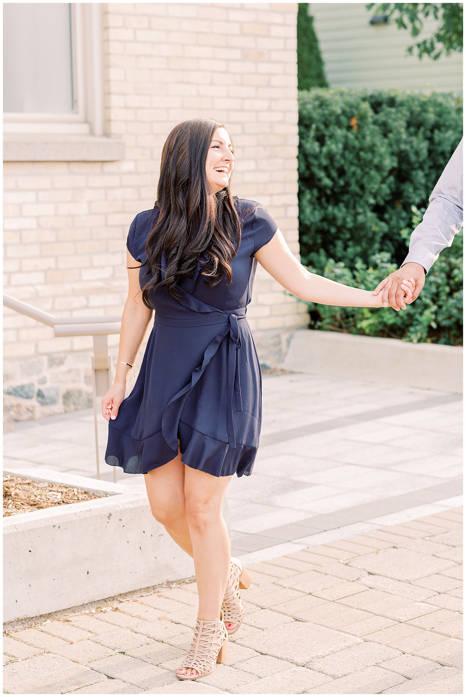 Woman laughing and holding husband's hand while walking